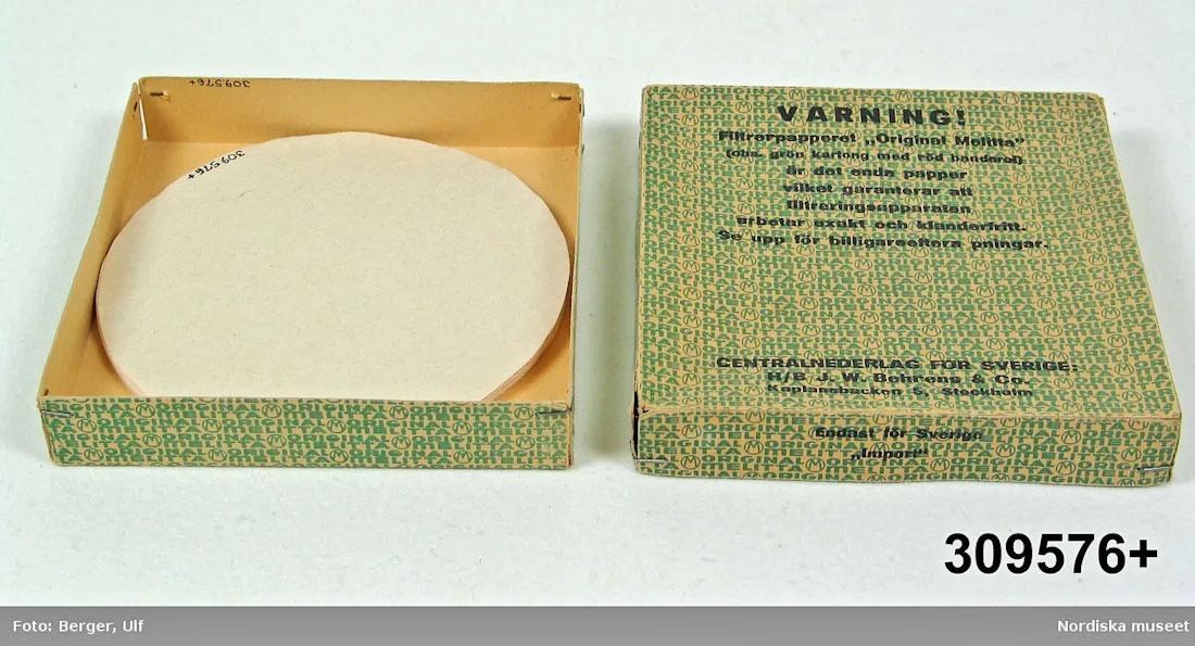 Scatola storica di filtri di carta rotondi Melitta con grafica verde e scritta “Varning!” in svedese, confezione aperta con dischi filtranti a vista.