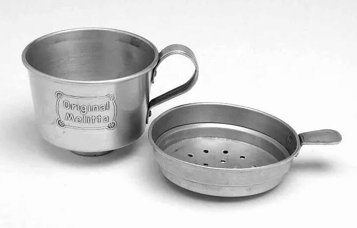 Filtro per caffè “Original Melitta” in metallo con tazza e supporto perforato separato, primo modello storico legato all’evoluzione dei filtri di carta.